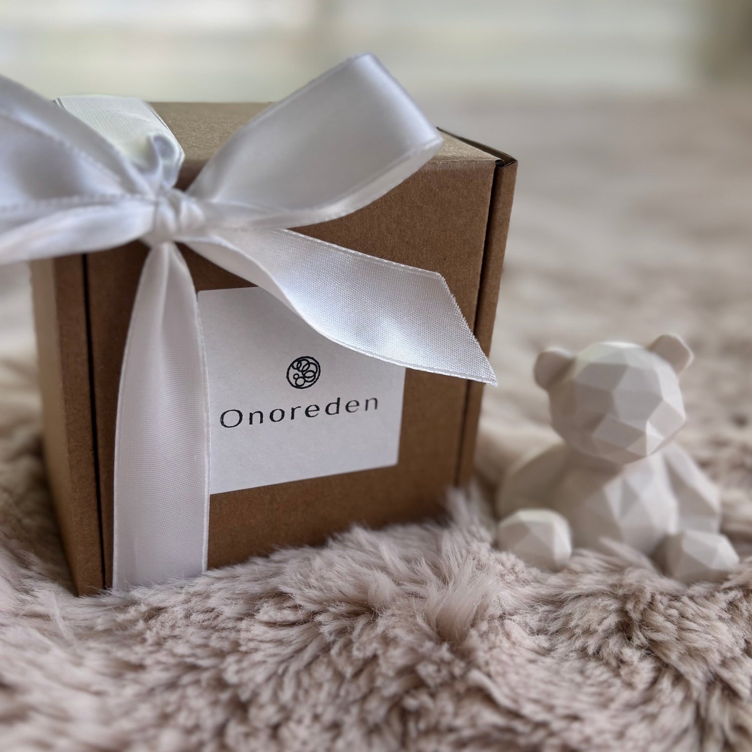 Handmade gift boxes with ribbons and sculptural decor pieces styled on soft fabric.