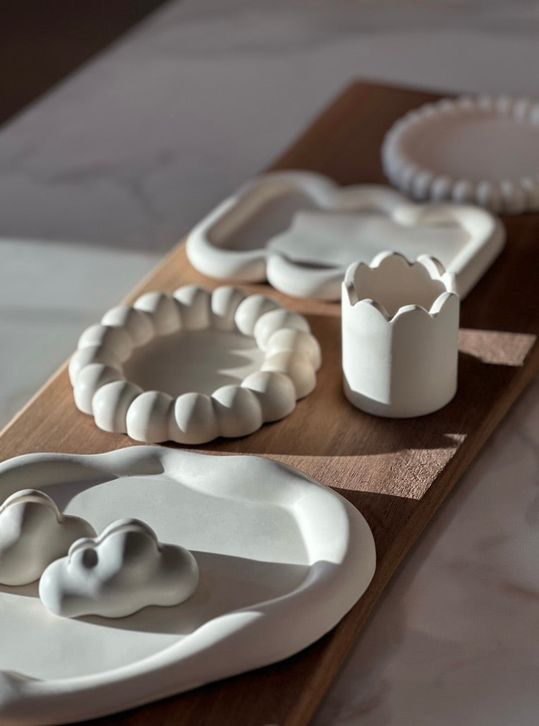 Minimalist sculptural decor pieces displayed on a wooden table in natural light, showcasing new arrivals.