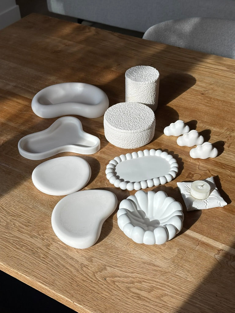 Minimalist sculptural decor pieces displayed on a wooden table in natural light, showcasing new arrivals.