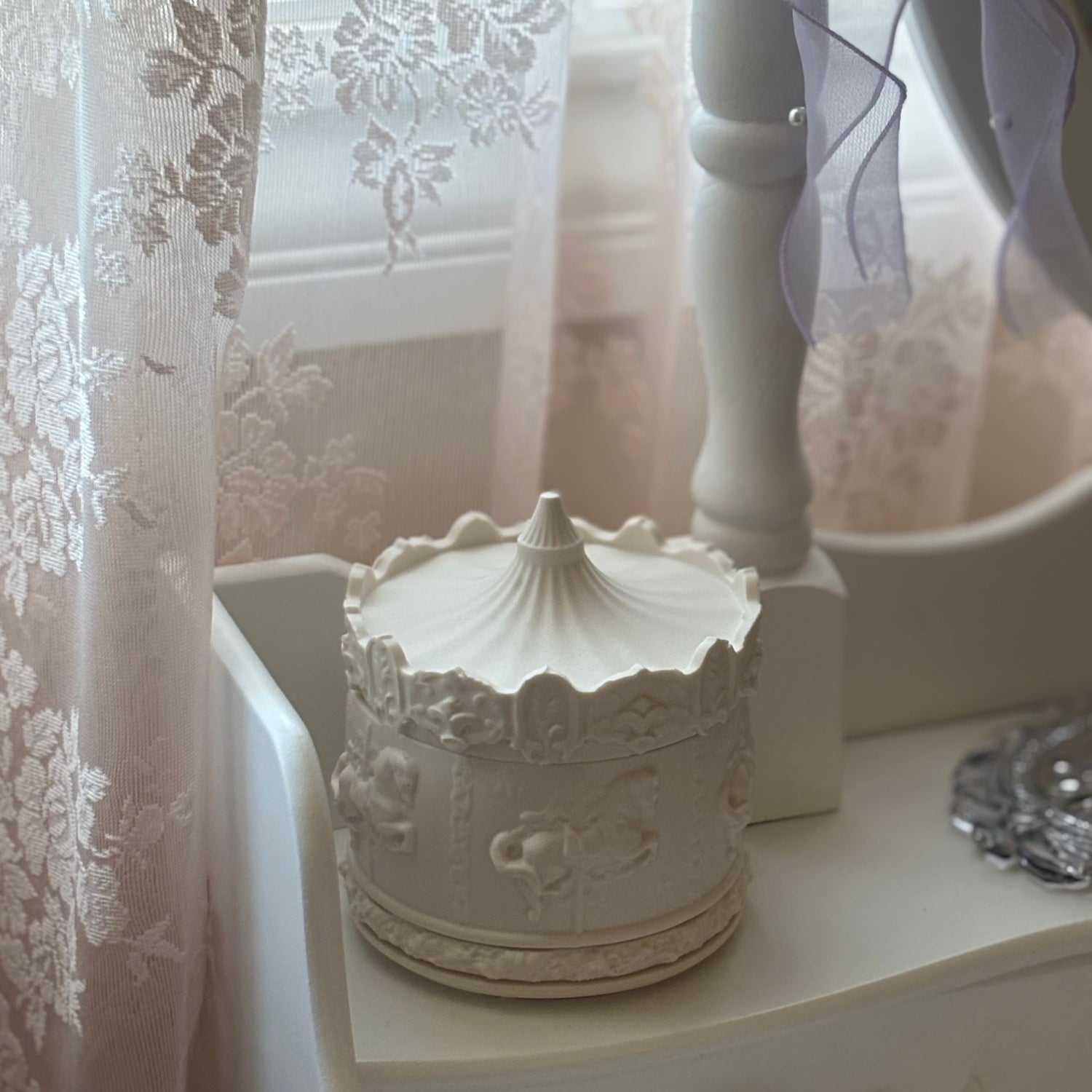 Collection of sculptural white containers with textured surfaces styled on a wooden floor in soft natural light.